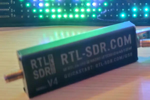 An RTL-SDR Blog V4 dongle on the bench in front of the OrcSDR LED sign