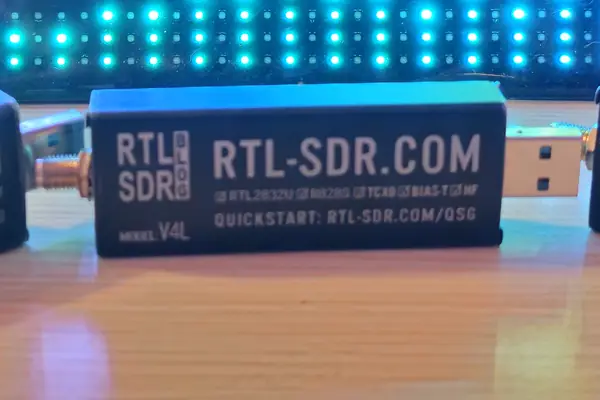 An RTL-SDR Blog V4L dongle on the bench in front of the OrcSDR LED sign